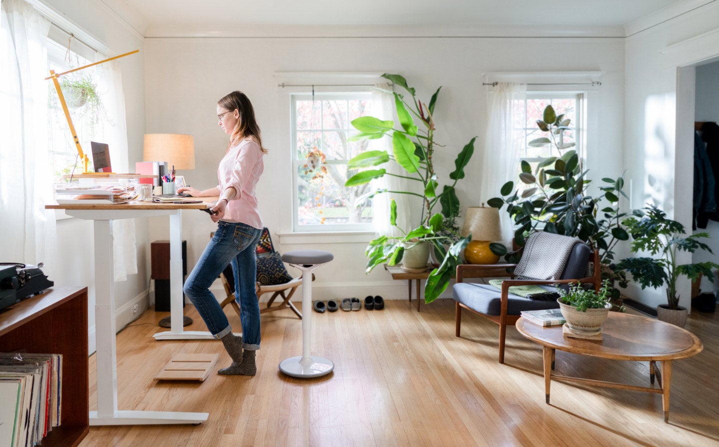 woman is working on a table and some plants are in background showing a fresh indoor environment.