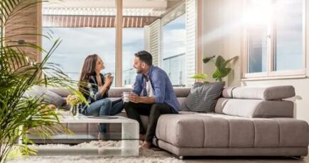 a couple sitting on couch in a fresh home environment in a happy mode, indoor plants also can be seen in picture.
