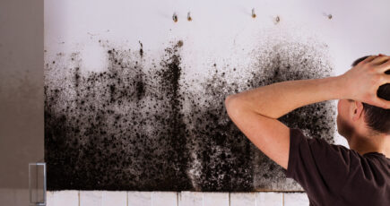 man worried after seeing black mold on wall.